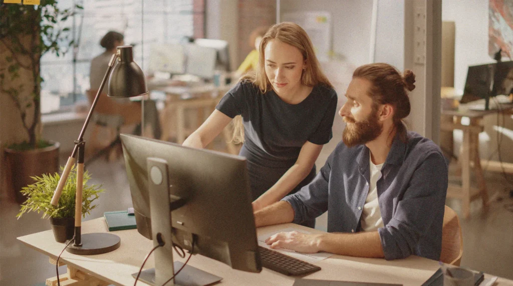 Two adults looking at a computer together.